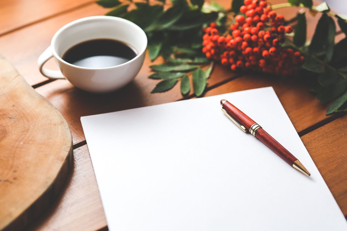 An open notebook and pen on a wooden desk beside a window